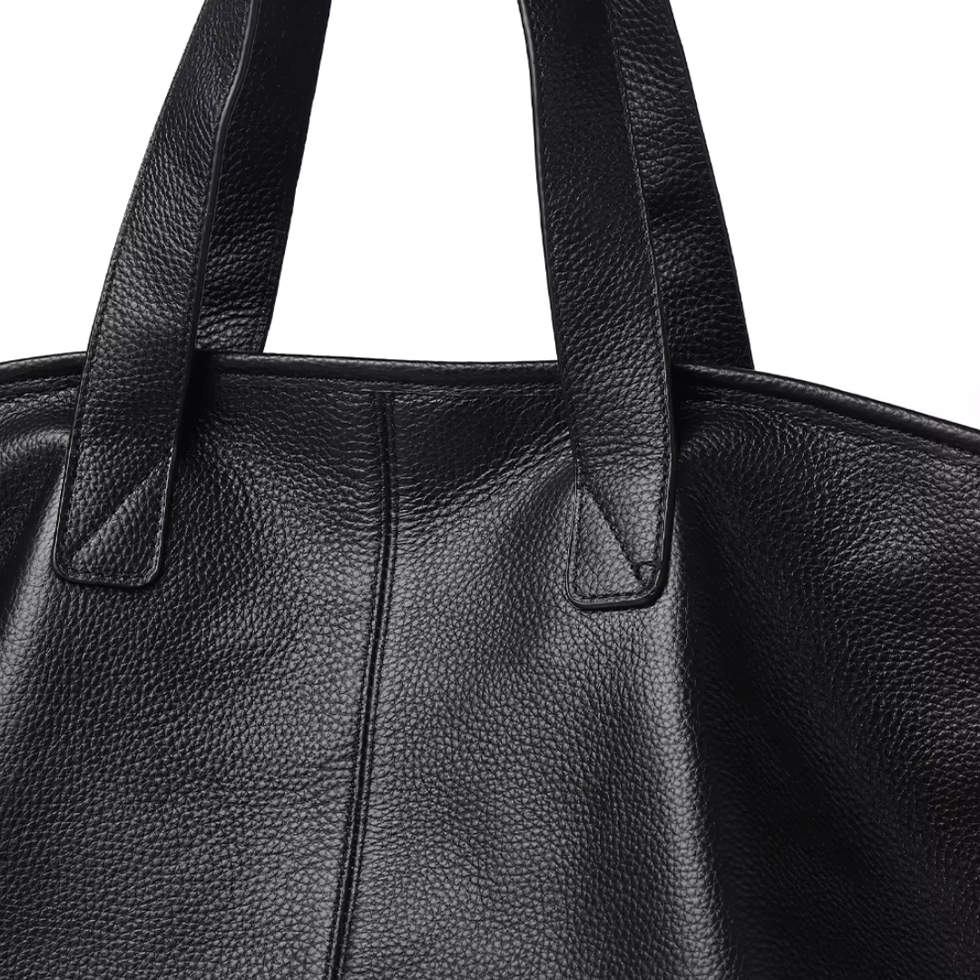 Close-up of premium genuine leather grain texture and double-stitched handles on The Celeste
