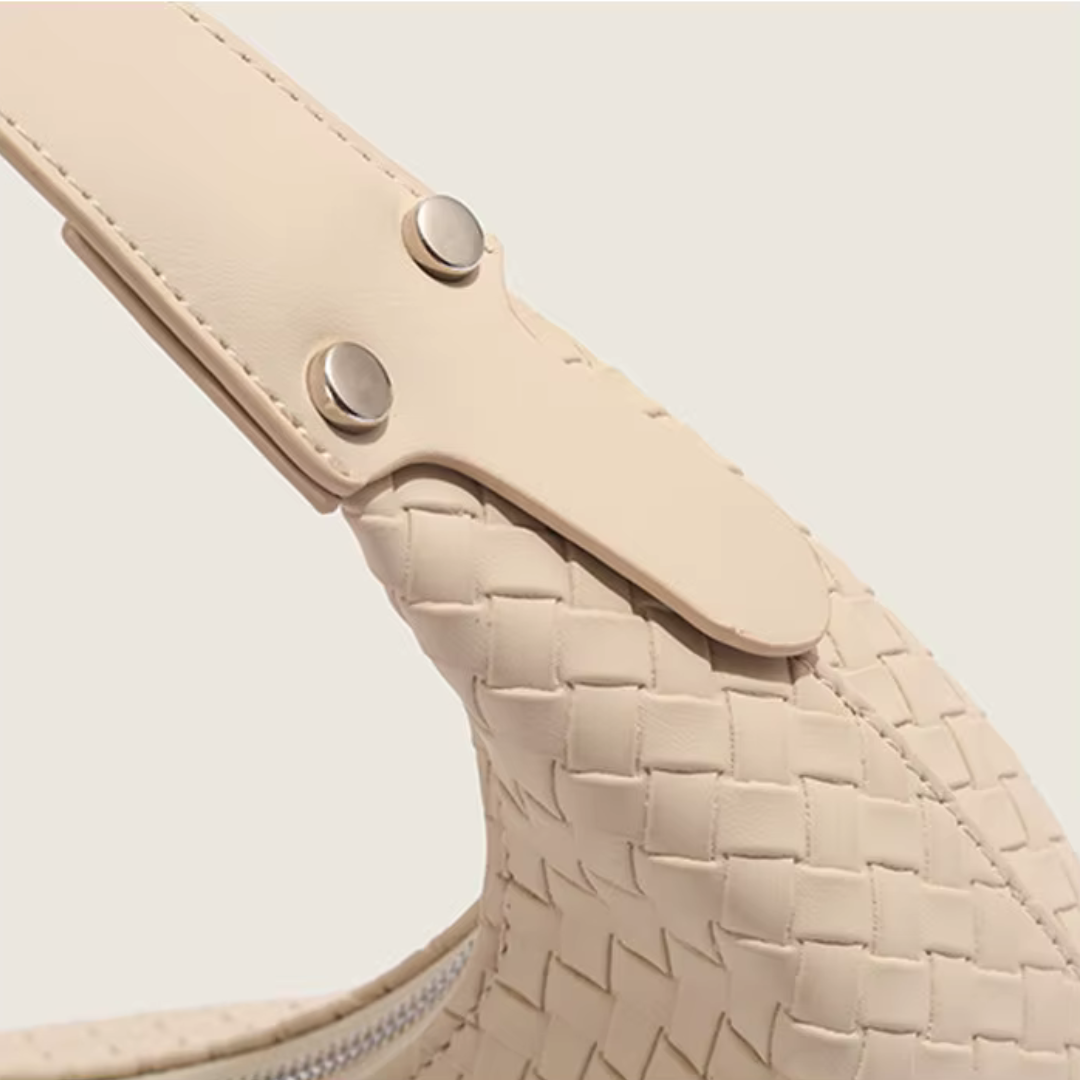 Close-up of adjustable strap hardware and woven leather texture in soft ivory